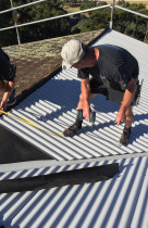 Decramastic Roof Replacement with Colorsteel Roofing products - The team is installing Colorsteel Corrugated roofing sheets, working face by face around the roof. When all the sheets were laid, measurements were taken for the custom made flashings.