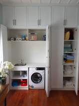 Built in Laundry - Large Villa with a high roof needed a wall length of units to hide a small laundry and allows for plenty of cupboard space above and on the right side of the laundry.
The Laundry sits behind Bi-folding doors that line up with the top cupboard doors when closed.