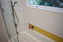 Northcote bathroom tiling completed by Bathroom and Tiling Ltd - 600x300mm white porcelain wall tiles. Mitered edges. Yellow mosaic to soap box recess.