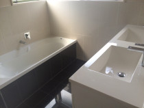 Handy Home Solutions - Double vanity with dark floor and bath front tiles.